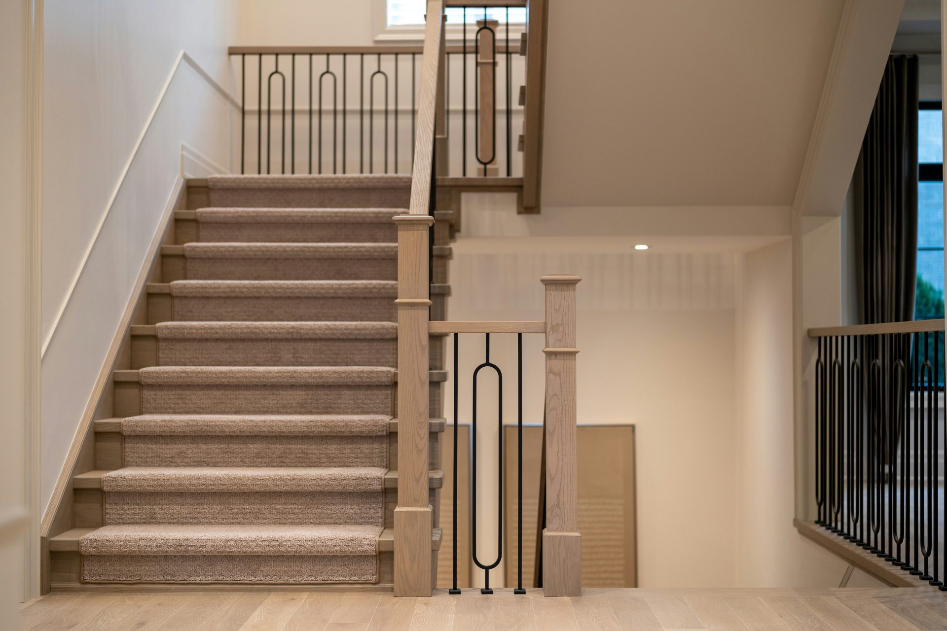 A modern staircase with carpeted steps and elegant metal railings.