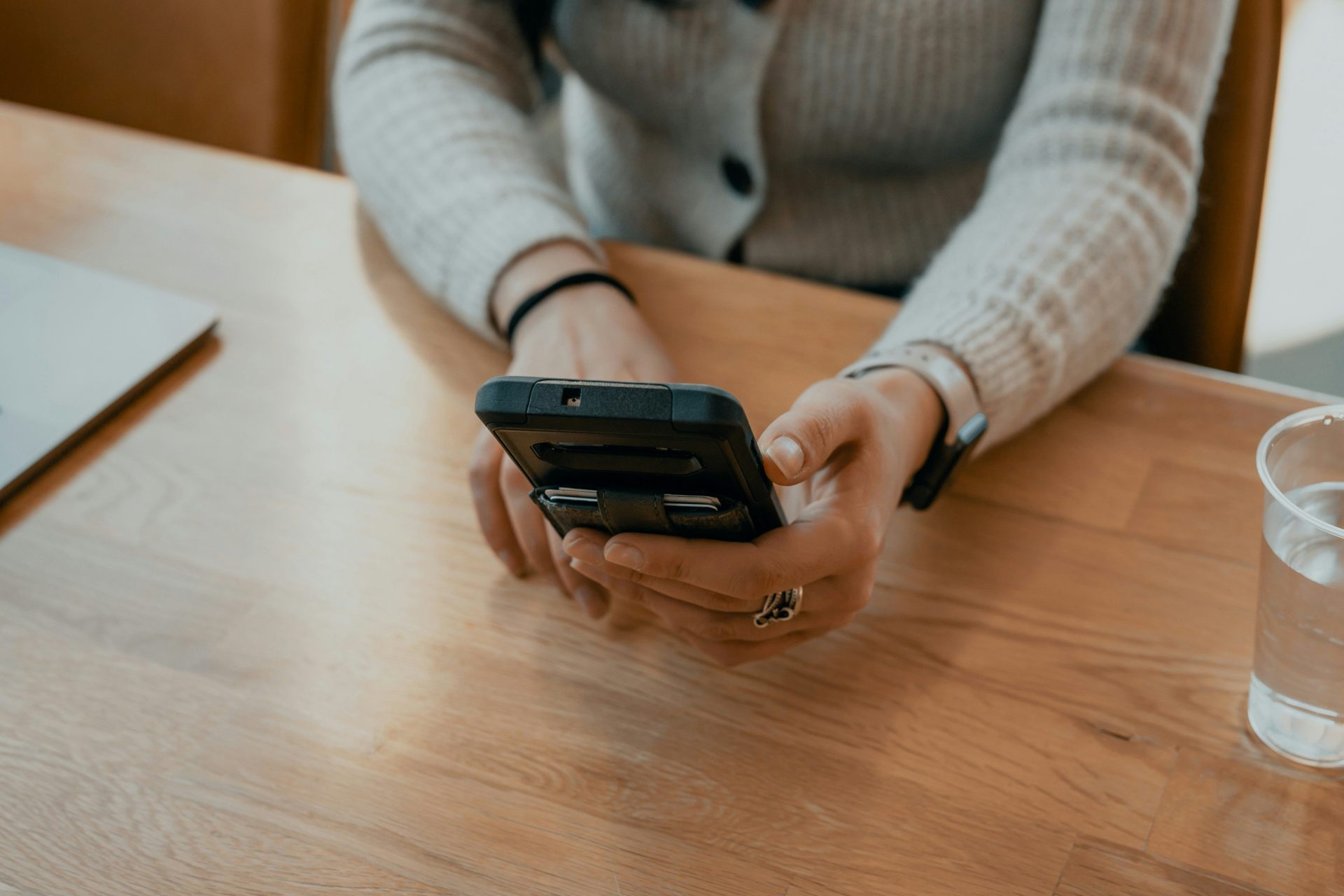 Femme en pull blanc tenant un smartphone noir